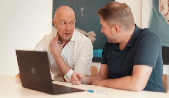Två kollegor jobbar vid en laptop
