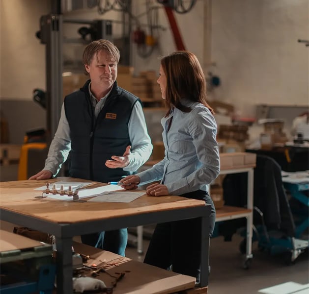 Two people discussing solutions at a table with a composite article
